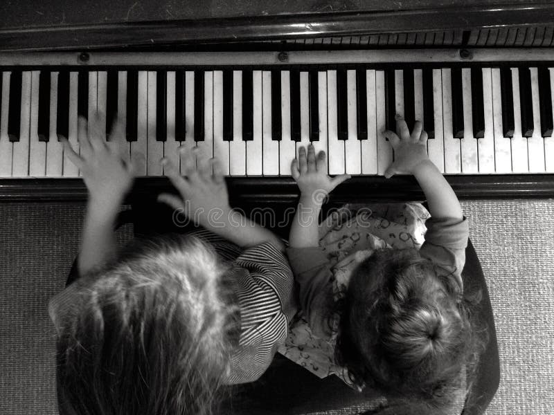 Two children (girls age 05 and 2) play music on piano. Aerial point of view. Two children (girls age 05 and 2) play music on piano. Aerial point of view