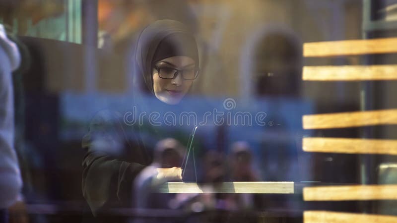 Мусульманская дама в традиционной одежде беседуя на плате сидя в кафе, современной жизни стоковые изображения Мусульманская дама в традиционной одежде беседуя на плате сидя в кафе, современной жизни стоковые изображения