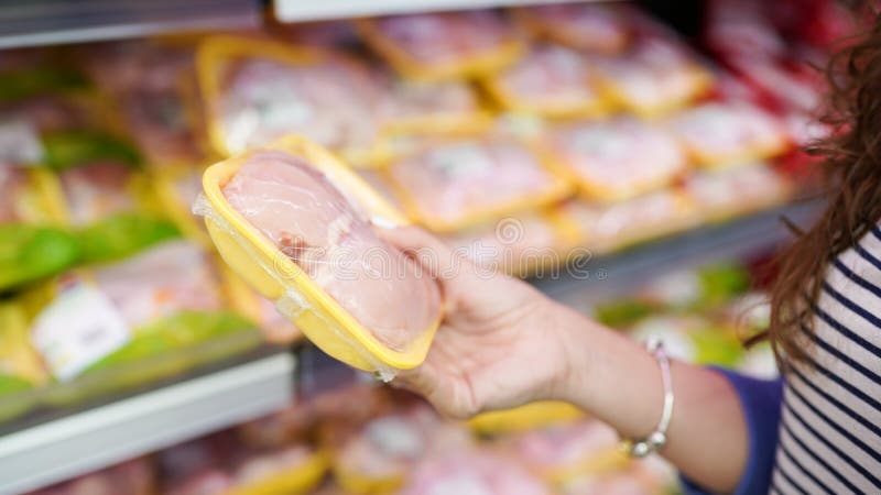 Мясо в продовольственном магазине Женщина выбирая упаковала свежее мясо цыпленка в супермаркете стоковое изображение rf Мясо в продовольственном магазине Женщина выбирая упаковала свежее мясо цыпленка в супермаркете стоковое изображение rf