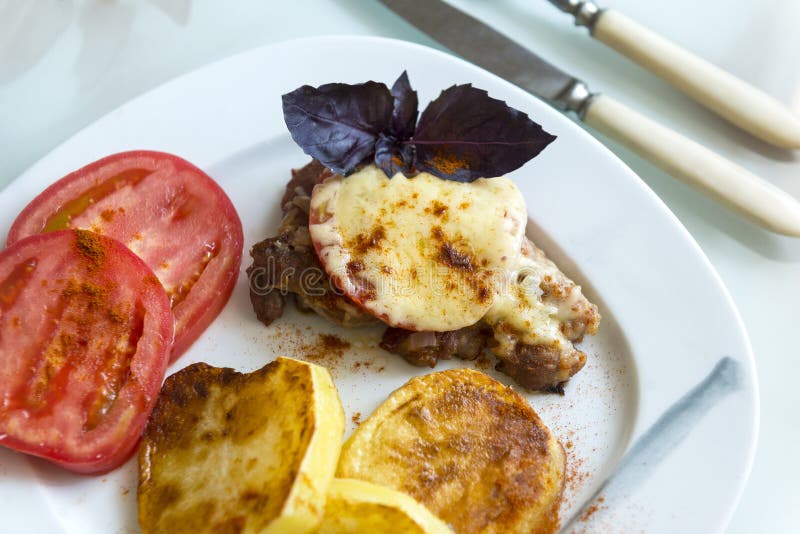 Мясо испекло под сыром с томатом и картошками с специями дальше стоковые изображения Мясо испекло под сыром с томатом и картошками с специями дальше стоковые изображения