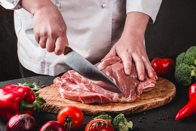 Мясо свинины вырезывания мясника шеф-повара с ножом на кухне, варя еду стоковые фотографии rf Мясо свинины вырезывания мясника шеф-повара с ножом на кухне, варя еду стоковые фотографии rf