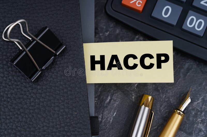 на столе калькулятор ручка и ноутбук с закладкой, на которой написано haccp стоковое изображение