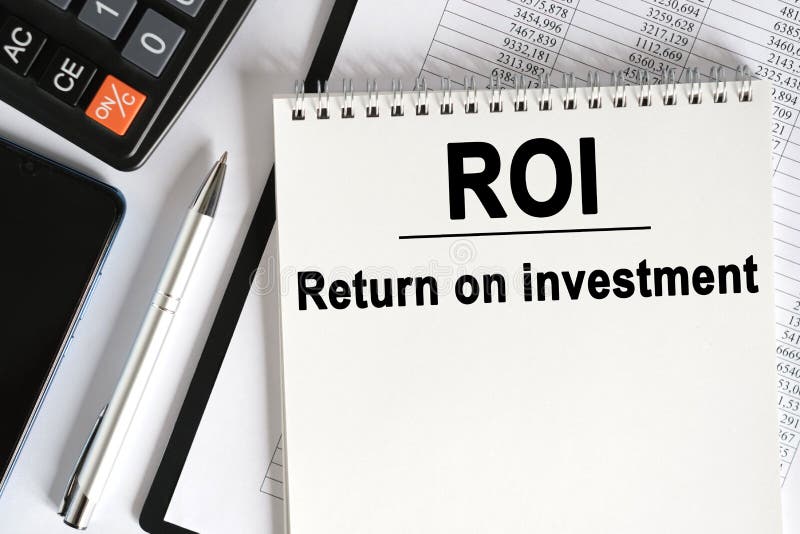 На столе лежит смартфон калькулятор и ноутбук с roi надписи стоковые изображения