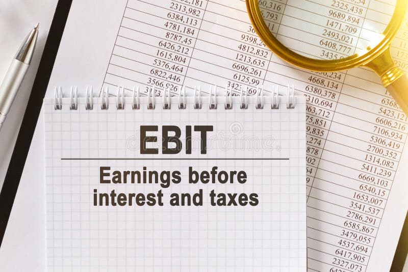 На столе финансовые отчеты ручка лупа и ноутбук с ebit надписи стоковая фотография