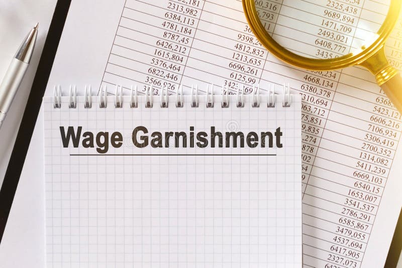 На столе финансовые отчеты ручка лупа и ноутбук с garnishment зарплаты надписи стоковое изображение