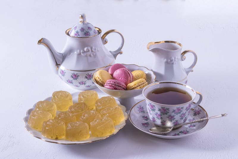 Набор чая фарфора с молоком, макаронами и мармеладом, кувшином молока, чашкой чая, чашкой и поддонником, камедеобразной конфетой стоковая фотография Набор чая фарфора с молоком, макаронами и мармеладом, кувшином молока, чашкой чая, чашкой и поддонником, камедеобразной конфетой стоковая фотография
