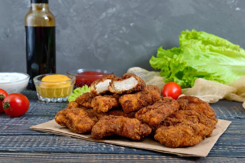 Наггеты цыпленка Части глубок-зажаренного кудрявого мяса, на бумаге с различными соусами на деревянном столе стоковое изображение rf