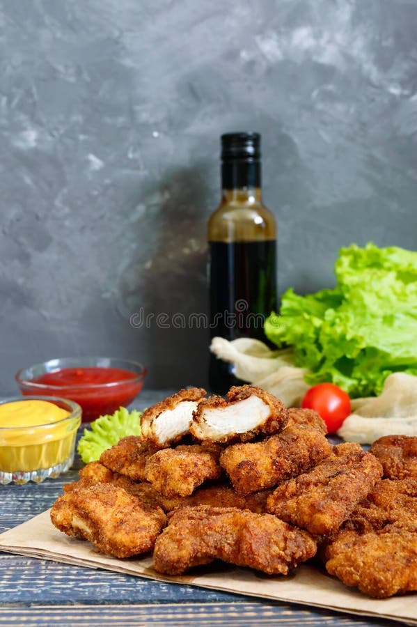 Наггеты цыпленка Части глубок-зажаренного кудрявого мяса, на бумаге с различными соусами на деревянном столе стоковое фото