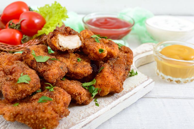 Наггеты цыпленка Части глубок-зажаренного кудрявого мяса, на бумаге с различными соусами стоковая фотография