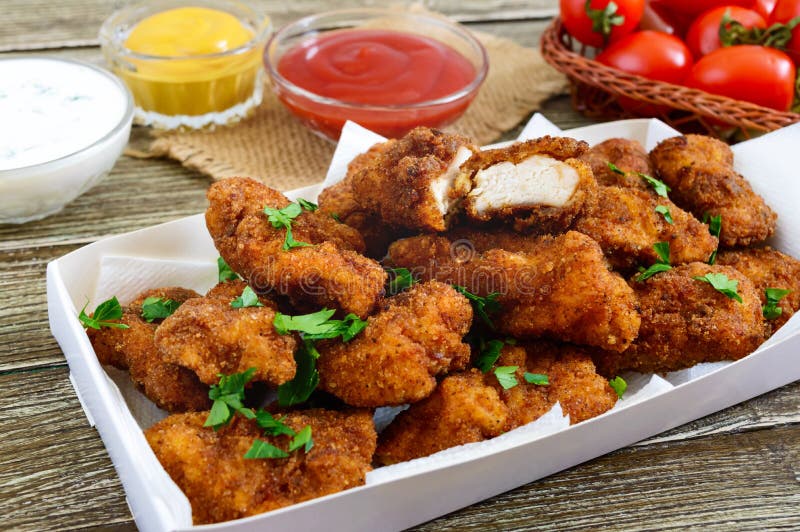 Наггеты цыпленка Части глубок-зажаренного кудрявого мяса, с различными соусами на деревянном столе стоковые фото