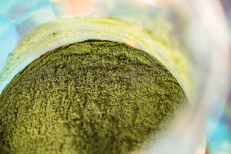 Надземный взгляд крупного плана опарника с свежим зеленым порошком spirulina на кухонном столе стоковые фото