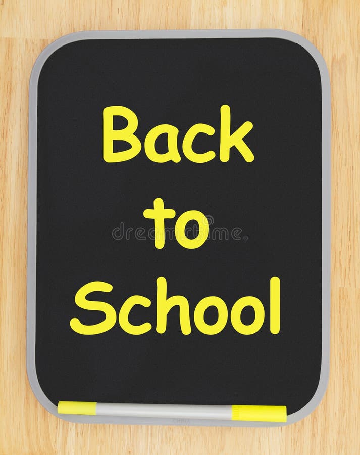 Back to School message on black dry erase board with marker on wood textured wall with copy space for your message. Back to School message on black dry erase board with marker on wood textured wall with copy space for your message