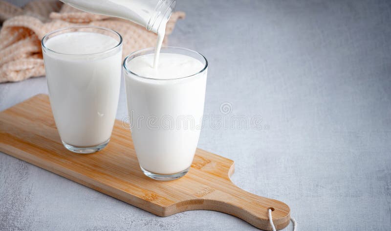 Pouring homemade kefir, buttermilk or yogurt with probiotics. Yogurt flowing from glass bottle on light background. Probiotic cold fermented dairy drink. Trendy food and drink. Copy space. Pouring homemade kefir, buttermilk or yogurt with probiotics. Yogurt flowing from glass bottle on light background. Probiotic cold fermented dairy drink. Trendy food and drink. Copy space.