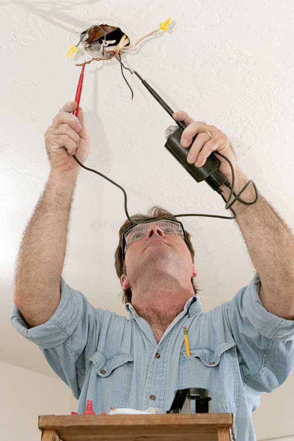 An electrician testing the voltage coming out of ceiling wires. Work is being performed to code by a licensed master electrician. An electrician testing the voltage coming out of ceiling wires. Work is being performed to code by a licensed master electrician.