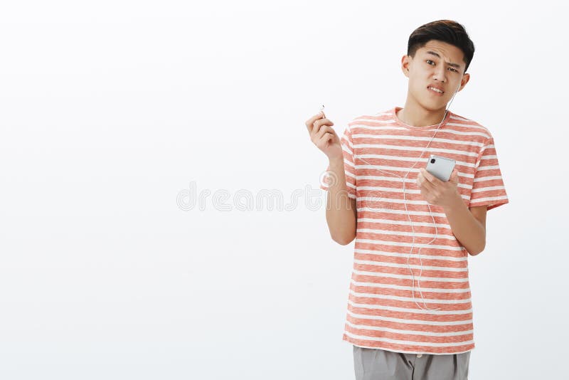 Наушники сломали вниз, парень нарушенный при ужасный звук, принимая earbud хмурясь и поворачивая далеко от наушников азиатско стоковые фото Наушники сломали вниз, парень нарушенный при ужасный звук, принимая earbud хмурясь и поворачивая далеко от наушников азиатско стоковые фото
