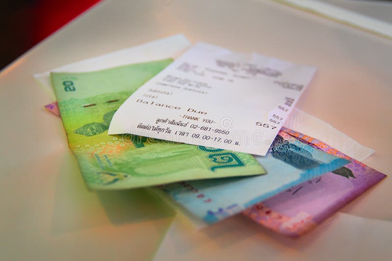 Национальная валюта бата Таиланда при проверка наличных денег лежа на таблице Измените THB и проверку после обедающего на кафе де