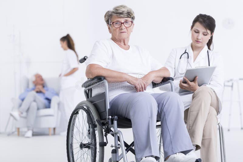 Cropped shot of a sad female patient in a wheelchair next to her doctor. Cropped shot of a sad female patient in a wheelchair next to her doctor