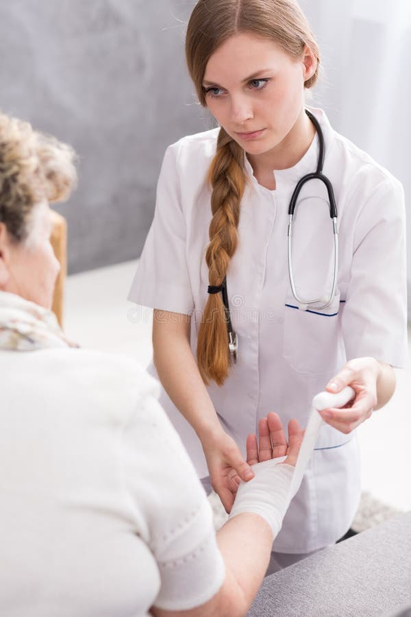 Shot of a young nurse bandaging her patient's hand. Shot of a young nurse bandaging her patient's hand