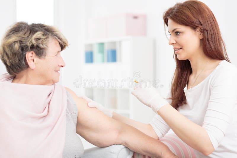 Shot of a young nurse making an injection to a smiling senior woman. Shot of a young nurse making an injection to a smiling senior woman