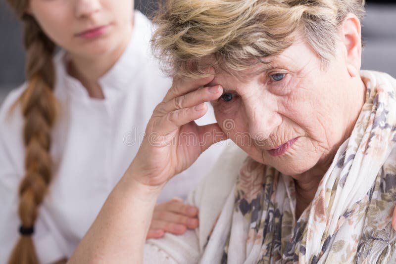 Shot of a concerned senior women and a nurse sitting behind her and holding her arm. Shot of a concerned senior women and a nurse sitting behind her and holding her arm