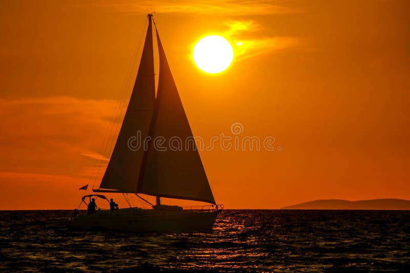 Sailboat at sea close-up, sunset, orange sky, big sun. Sailboat at sea close-up, sunset, orange sky, big sun