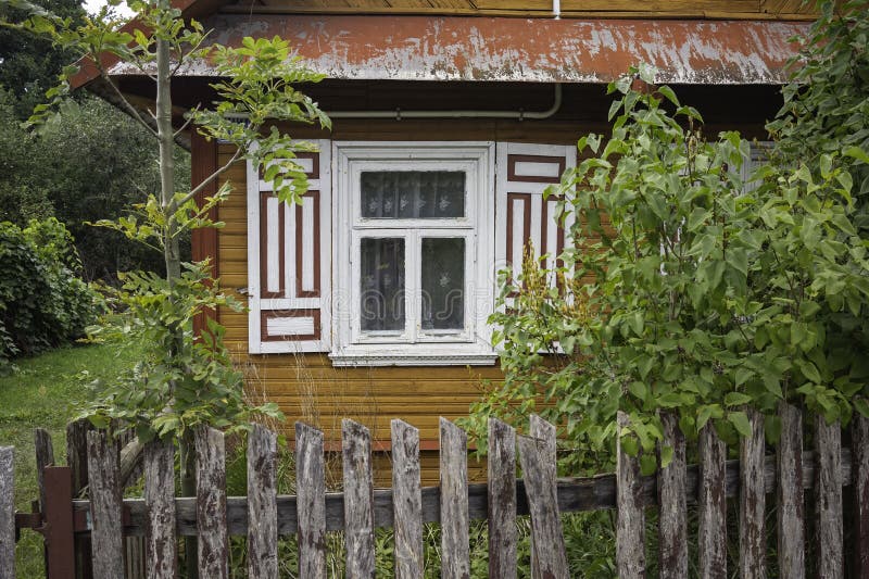 Небольшой дом с белым окном и деревянным забором стоковые изображения rf