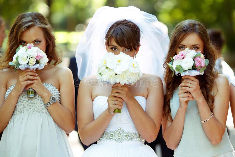 Невеста и bridesmaids прячут их стороны за меньшим bou свадьбы стоковое изображение Невеста и bridesmaids прячут их стороны за меньшим bou свадьбы стоковое изображение