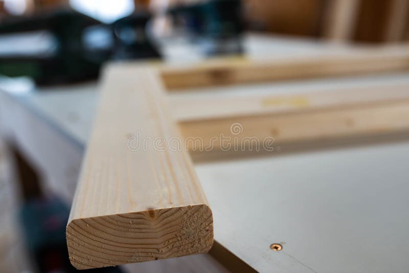 Unfinished bed frame on the table, wood sanders in row on the blured background. Unfinished bed frame on the table, wood sanders in row on the blured background.