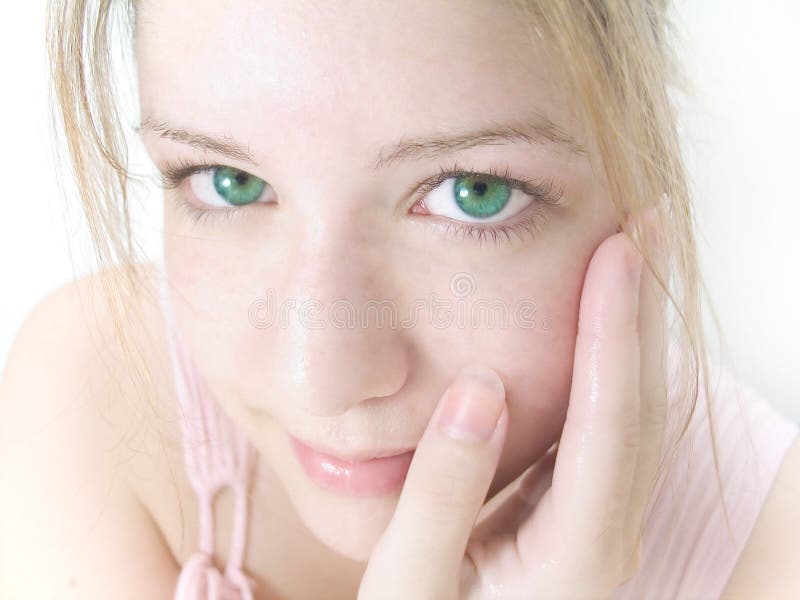 Woman staring into the camera after splashing water over face, high key, pale pink tones, green eyes. Crisp focus on the eyes. Woman staring into the camera after splashing water over face, high key, pale pink tones, green eyes. Crisp focus on the eyes.