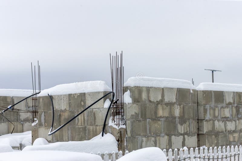 Unfinished building made of concrete blocks and sticking out rusty fittings, winter scene. Unfinished building made of concrete blocks and sticking out rusty fittings, winter scene