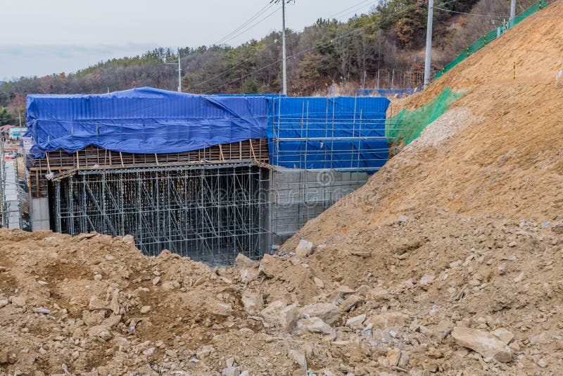 Unfinished concrete structure partially covered with blue tarp at new construction site. Unfinished concrete structure partially covered with blue tarp at new construction site