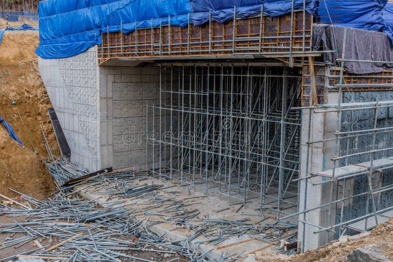 Unfinished concrete structure partially covered with blue tarp at new construction site. Unfinished concrete structure partially covered with blue tarp at new construction site