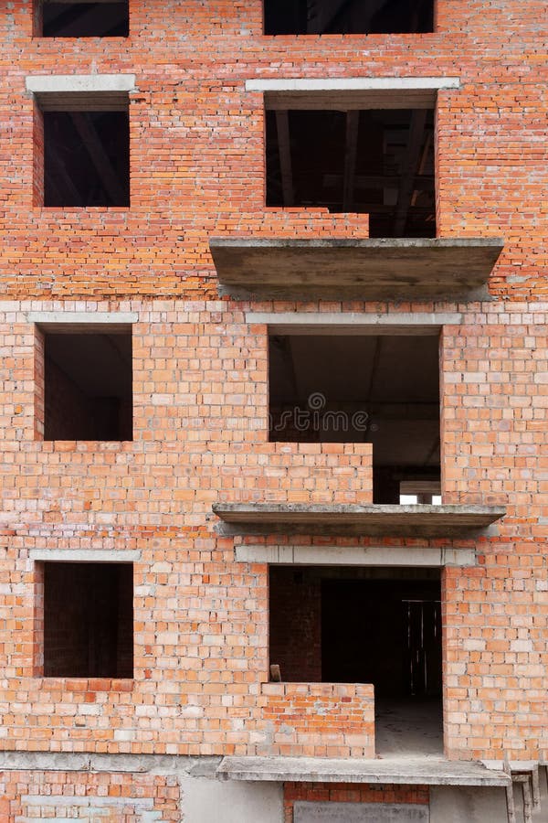 Photo of unfinished brick building with many window and balcony. Photo of unfinished brick building with many window and balcony