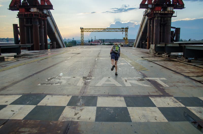 Unfinished metal bridge. Girl at the start line. Abandoned industrial landscape at sunset. Unfinished metal bridge. Girl at the start line. Abandoned industrial landscape at sunset