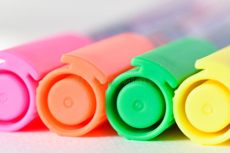 Caps of four different neon colored felt tip pens, used for marking text elements out of one production line series. Caps of four different neon colored felt tip pens, used for marking text elements out of one production line series