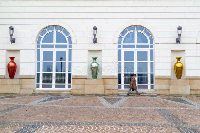 An unidentified executive in Luxembourg hurrying up along foreside of an administration building with glassy vase sculptures in front of it - Luxembourg City, Luxembourg (Grand Duchy of Luxembourg), April 3 2015. An unidentified executive in Luxembourg hurrying up along foreside of an administration building with glassy vase sculptures in front of it - Luxembourg City, Luxembourg (Grand Duchy of Luxembourg), April 3 2015