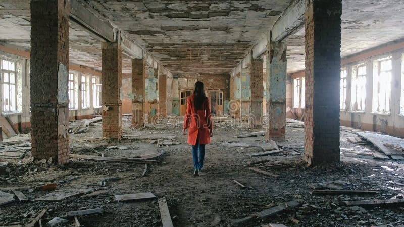 Непознаваемая женщина в красном плаще проверяет разрушенное здание после землетрясения бедствия, поток, огонь стоковое изображение rf Непознаваемая женщина в красном плаще проверяет разрушенное здание после землетрясения бедствия, поток, огонь стоковое изображение rf