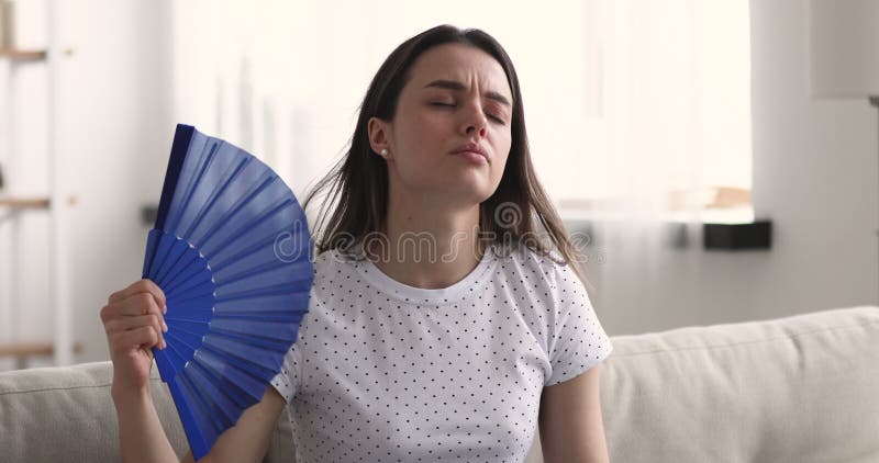 Несчастная женщина, размахивая горячее чувство вентилятора неудобное дома