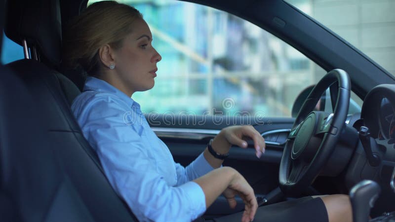 Несчастная женщина сидя в автомобиле, вымотанном после трудного перегружанного рабочего дня