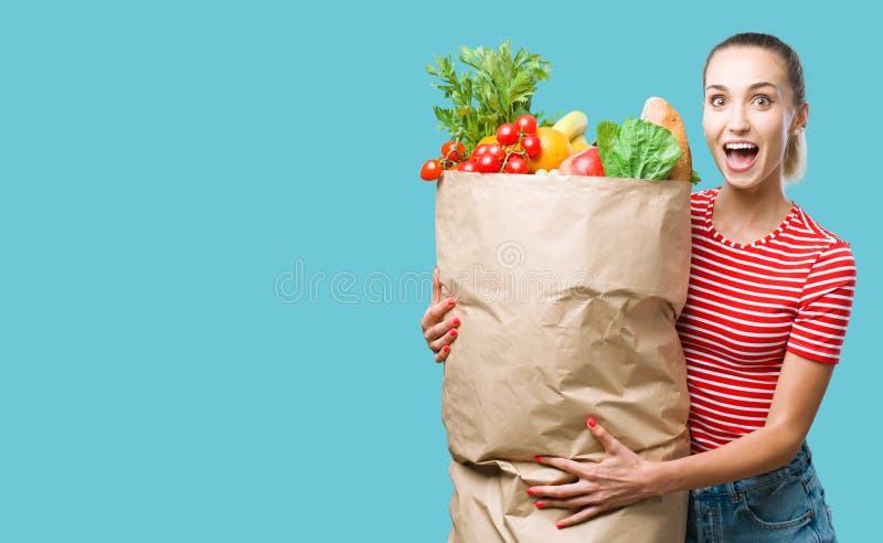 Неунывающая молодая женщина с продуктовую сумку, наполненный овощей стоковое изображение