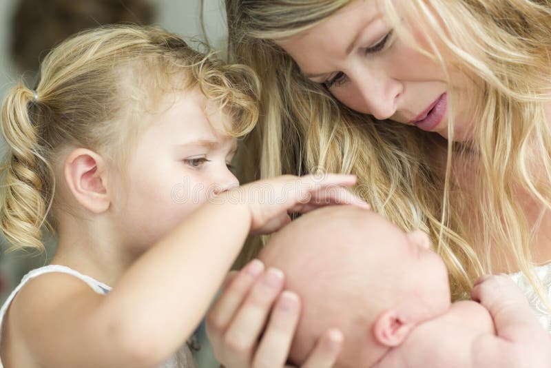 Новая мать держит Newborn ребёнок по мере того как молодая сестра смотрит стоковая фотография