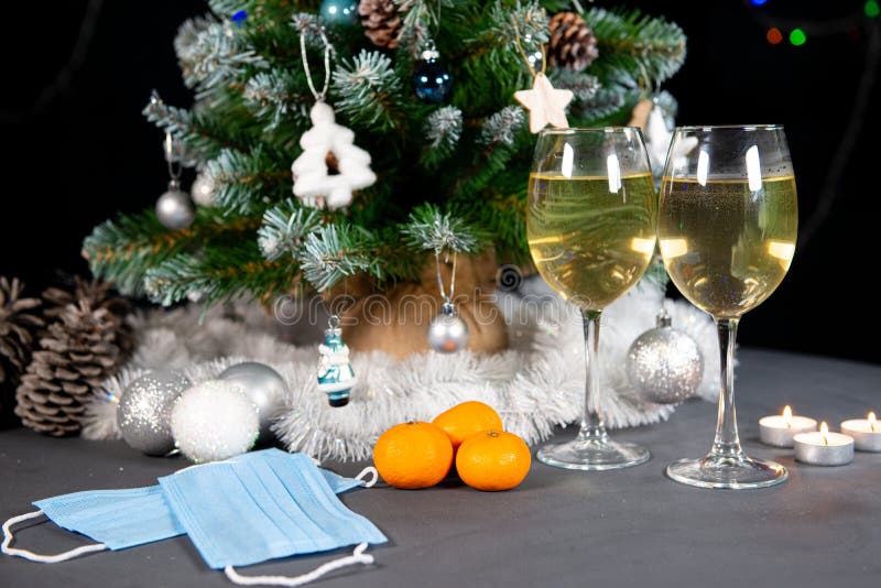 New year`s still life, 2 glasses of champagne tangerines on the table on the background of the Christmas tree. black background. New year`s still life, 2 glasses of champagne tangerines on the table on the background of the Christmas tree. black background