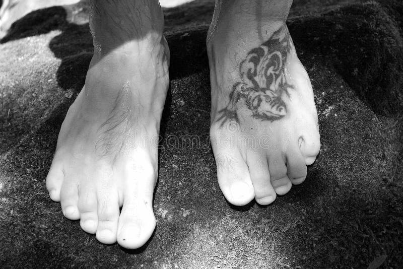 Black and white feet and a big tattoo. Black and white feet and a big tattoo