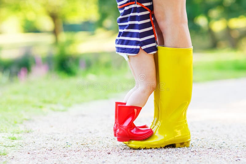 Ноги молодой женщины и ее daugher маленькой девочки в rainboots