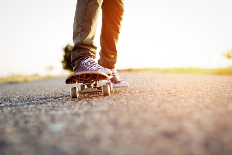 Legs on the new skateboard lightened by the sun. Legs on the new skateboard lightened by the sun