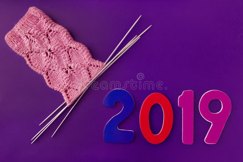 Номера деревянное 2019 и розовые носки сделанные из шерстей, связали с openwork картиной на 4 вязать иглах на пурпурной предпосыл стоковые изображения