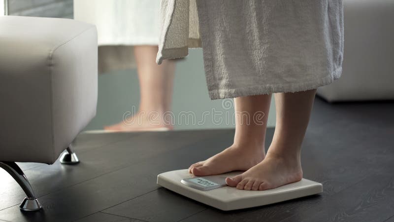 Нормальный вес, девушка проверяя dieting результаты в масштабах дома, здоровое тело стоковое изображение Нормальный вес, девушка проверяя dieting результаты в масштабах дома, здоровое тело стоковое изображение