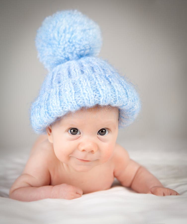 Infant wearing blue knit hat with a white background. Infant wearing blue knit hat with a white background.