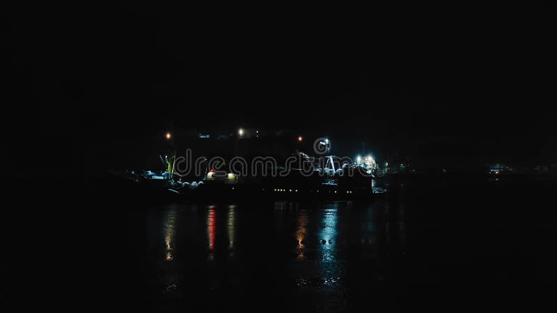 Ночью большое транспортное судно плавает недалеко от берега.