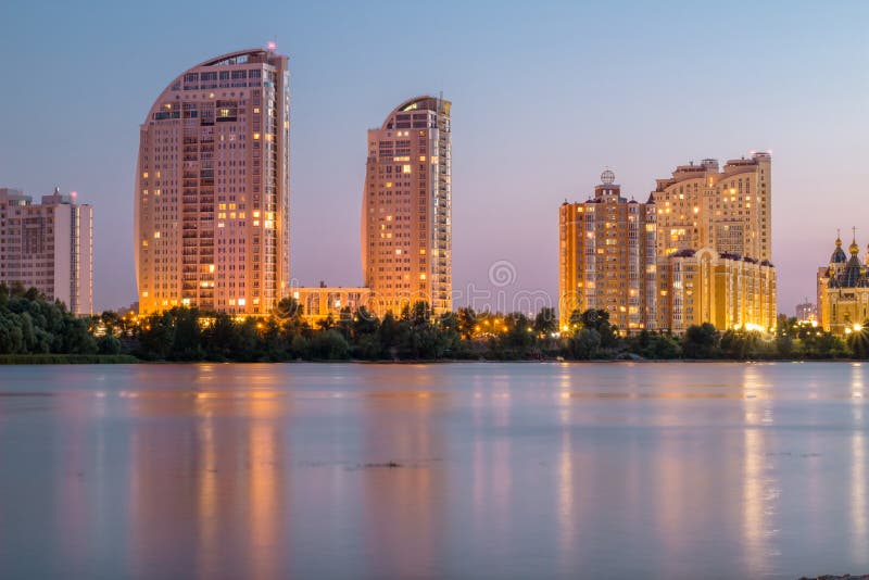 Lightened buildings reflected in river water. Night city. Lightened buildings reflected in river water. Night city